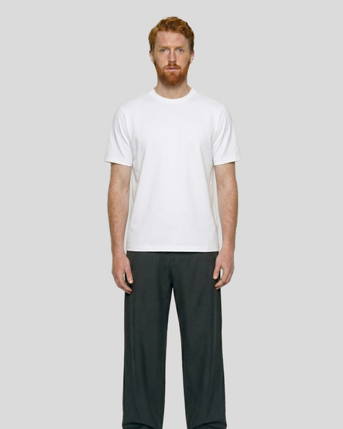Man wearing a white t-shirt and dark pants on a plain background