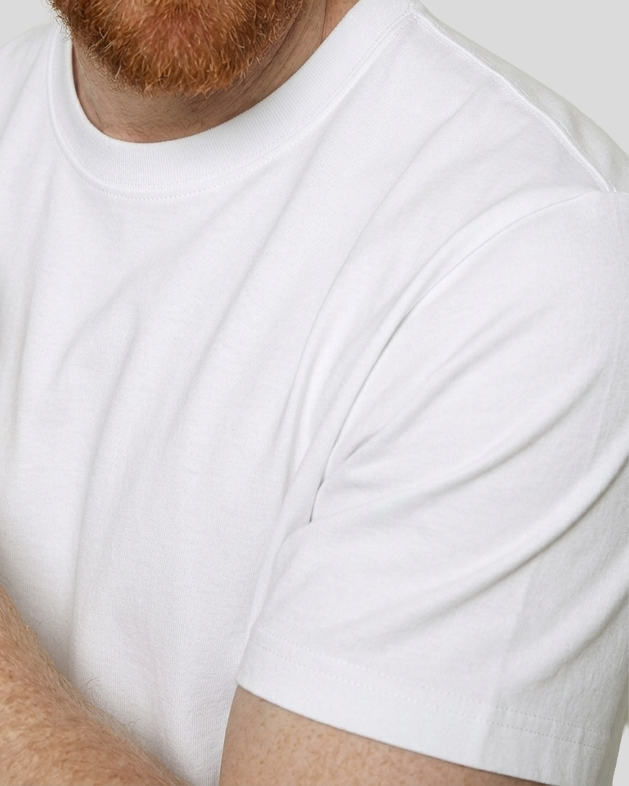 Close-up of a person wearing a plain white t-shirt against a light background