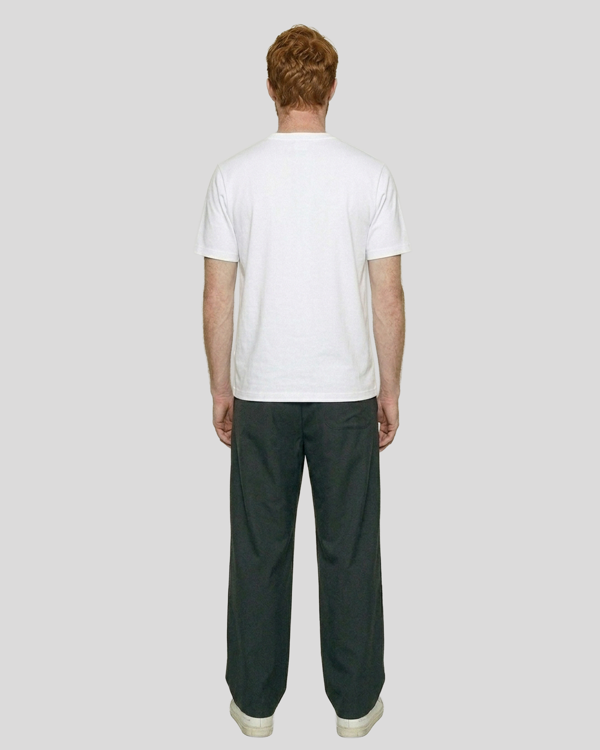 Person wearing a white t-shirt and dark pants on a plain background